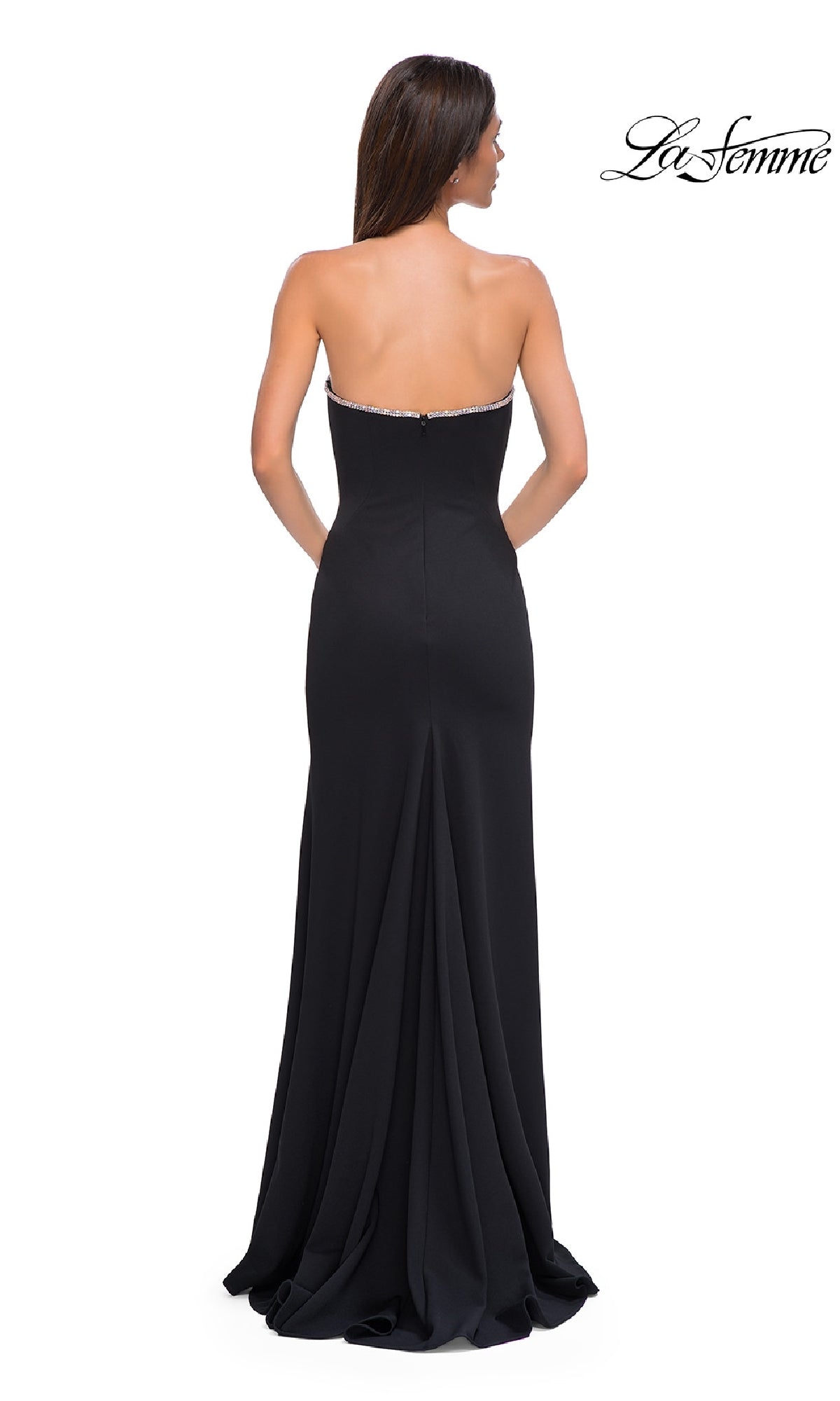 A woman with long brown hair models the Strapless Long Jersey Prom Dress: La Femme 32854, showing its fitted bodice and slight train from the back. The